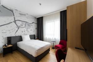 布雷达IntercityHotel Breda的酒店客房,配有一张床和一张红色椅子