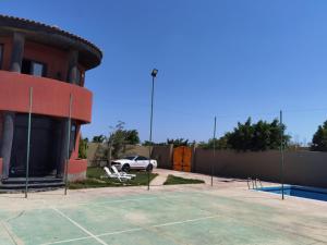 伯格埃拉伯Villa Mostafa Sadek, Swimming pool, Tennis & Squash - Borg ElArab Airport Alexandria的大楼前设有网球场的停车场
