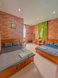 芹苴Hoàng Sơn's Home的一间卧室设有两张床和砖墙