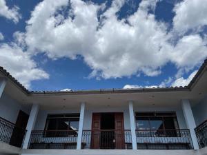 Chavín de HuantarHotel Restaurante Minas Cocha的蓝色天空和云的白色房子