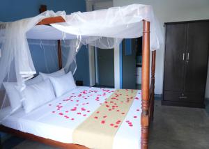 科斯戈德Darshana Beach Hotel的一张带红色鲜花的天蓬床