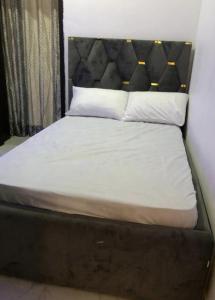 IkuataBeautiful 3-Bed House in Lekki的一张带黑色床头板、白色床单和枕头的床