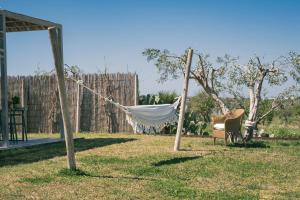 帕基诺NEW Exclusive Lodges, Marzamemi, Noto的庭院内的吊床,配有椅子和围栏
