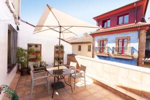 奥维多Green Hostel Oviedo的阳台的天井配有桌子和遮阳伞。