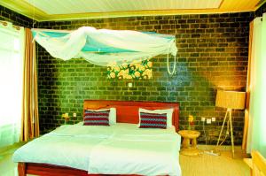 RuhengeriKarisimbi Cave Resort的一间卧室设有一张床和砖墙