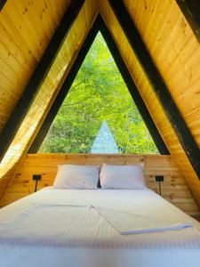 巴统A-Frame Rest-Art的木制客房的一张床铺,设有大窗户