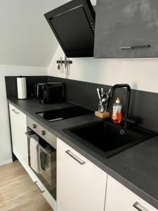 格拉茨Flores City Center Studio - Easy Self-Check-IN的厨房配有水槽和黑色台面