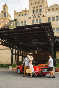 圣安东尼奥珠江河滨艾玛酒店 的一群站在一辆红车前面的人