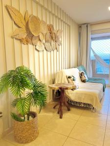 福塔莱萨Apartamentos no Condomínio Beach Village Fortaleza - Praia do Futuro - Por CasAmarInn的一间设有床、桌子和植物的房间