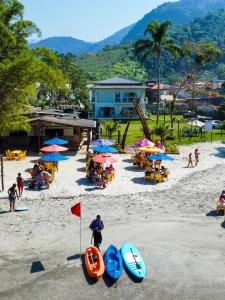 帕拉蒂Pousada Cantinho da Praia的海滩上有人,沙滩上摆放着椅子和遮阳伞