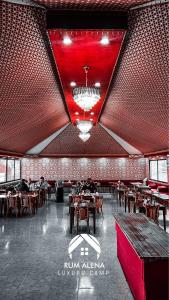 瓦迪拉姆RUM ALIENA LUXURY CAMP的餐厅拥有红色的天花板和桌椅