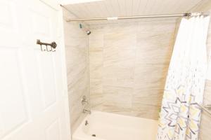 泽西市Mins from NYC Bright & Spacious 4-Bed Unit的带浴缸和淋浴帘的浴室