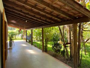 加罗帕巴Casa na Barra ampla e arejada com jardim incrível的开放式门廊,拥有木屋顶和树木