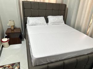 达累斯萨拉姆Rejao Homes的一张带白色床单和枕头的床