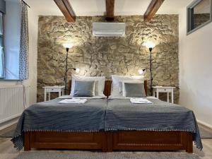 博尔多格克瓦劳尔尧Vitamin K73 Vendégház的一间卧室配有一张带两盏灯和石墙的床。