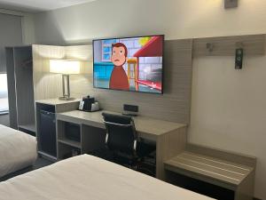 利明顿利明顿品质酒店的酒店客房设有一张桌子和一台墙上的电视。