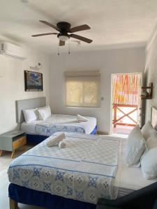 奥尔沃克斯岛Casa Coronaa Holbox México的一间卧室配有两张床和吊扇
