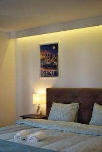 扎芬特姆Arku apartments Brussels Airport的一间卧室配有一张带灯和照片的床