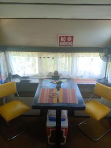 奥拉涅斯塔德Backpack Cabin A 49149的一张桌子,上面有两把黄色椅子和禁烟标志