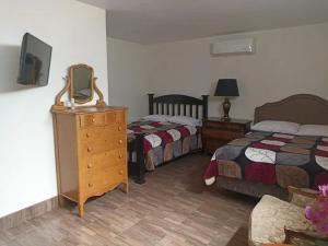 恩塞纳达港Casa María的一间卧室设有两张床和带电视的梳妆台。