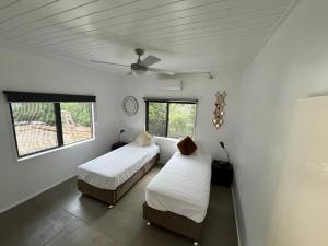 维拉港Elluk East Studios的配有2张床的白色墙壁和窗户客房