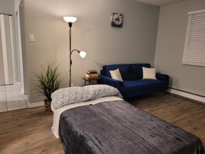 埃德蒙顿Entire 1-Bedroom Unit in Vibrant 124 Street Arts District的客厅配有床和蓝色沙发