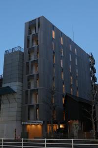 东京OHWA hostel minowa station的前面有棵树的黑色建筑
