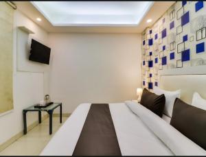 新德里Hotel Galaxy Stay B&B的一间卧室配有一张床,墙上配有电视