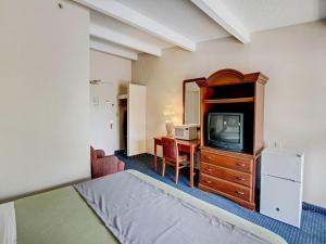 惠帕尼Scottish Inn Whippany的酒店的客房 - 带一张床、一台电视和一张书桌