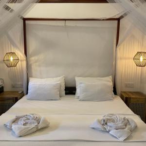 阿鲁甘湾Agra Arugambay的一张带白色床单的床和两张毛巾