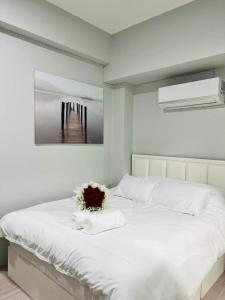 班敦孟Luna hotel สถานีดอนเมือง的卧室配有白色的床,床上插着花朵