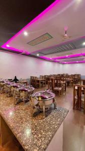 山姆Jaisalmer Unique Desert Camp的餐厅设有一排桌子和紫色灯