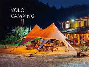 张家界Zhangjiajie YOLO Resort--Within Zhangjiajie National Forest Park的夜晚在院子里的一个橙色和白色的大帐篷