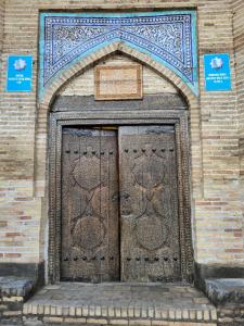 希瓦Orient Star Khiva Hotel- Madrasah Muhammad Aminkhan 1855的砖砌建筑中一个大木门