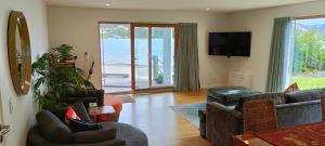 但尼丁New luxury waterfront accommodation的客厅配有沙发、椅子和电视