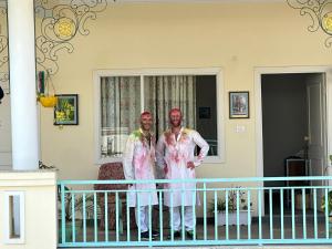 阿格拉Dá Bungalow - A Vacation Abode的两个人站在房子的阳台上