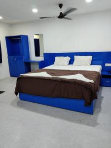 达曼HOTEL NEW RATNAKAR的一间卧室配有一张蓝色的床和棕色的毯子