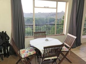 拉塞利亚Hills and Dales Accommodation的配有大窗户的客房内的桌椅