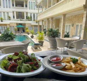 勒吉安巴厘岛庭院公寓及酒店的一张桌子,上面放着两盘食物和薯条