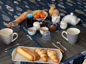Senneville-sur-FécampLe Caux ´Sy的一张桌子,上面放着一盘羊角面包和其他早餐食品