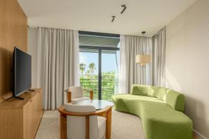 加瓦AC Hotel Gava Mar的客厅配有绿色沙发和电视