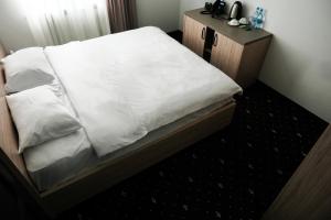 埃里温Colette Hotel的一张铺有白色床单的床和木制床头柜