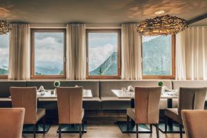 索内纳尔佩·纳斯费尔德Falkensteiner Family Hotel Sonnenalpe的餐厅设有桌椅和窗户。