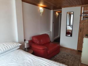 米尔登霍尔Mildenhall Suffolk的卧室配有红色椅子,位于床边