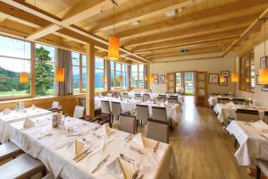 卡奇山口Falkensteiner Aktiv & Familienhotel Cristallo的餐厅设有白色的桌椅和窗户。