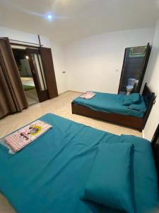Qaryat ash Shamālīشاليه للايجار اليومي بالريف الاوروبي的一间卧室配有两张床和一张蓝色床单