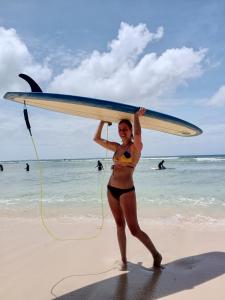 卢纳将军城sharkbunkbed siargao的海滩上一个穿着比基尼的女人,手持冲浪板