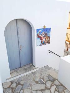 锡米"Zeus House" Sevasti Symi Studios的白色房间中的一扇蓝色门,画作