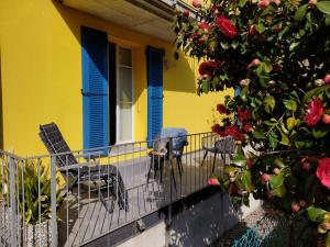布鲁西诺亚希吉欧Dolceresio Lugano Lake B&B的黄色房子,阳台上设有蓝色百叶窗和椅子
