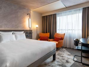 华沙华沙中心诺富特酒店的酒店客房带一张床、一张桌子和椅子